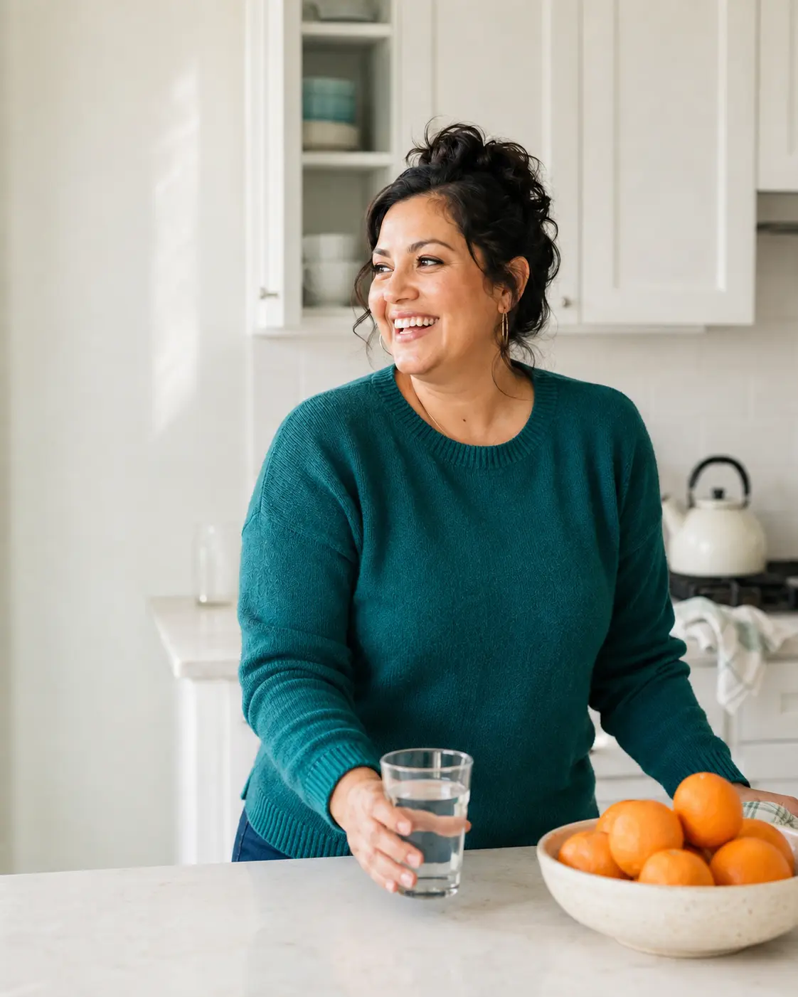 Member in a bright kitchen, teal knit, laughing mid-action